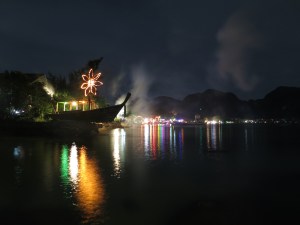 Loh Da Lum Bay (on Ko Phi Phi Don) at night, with the neon lights of its party bars lighting up the beach and bay.  The smoke is from a very large firework which had just been set off.
