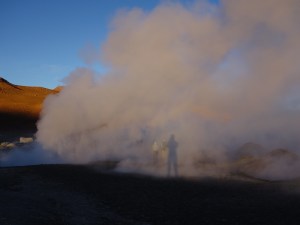 Casting a shadow on the steam from a geyser in the desert at sunrise in southern Bolivia